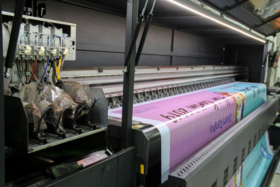 A large industrial printer feeding a long pink banner with printed text — stock style reference