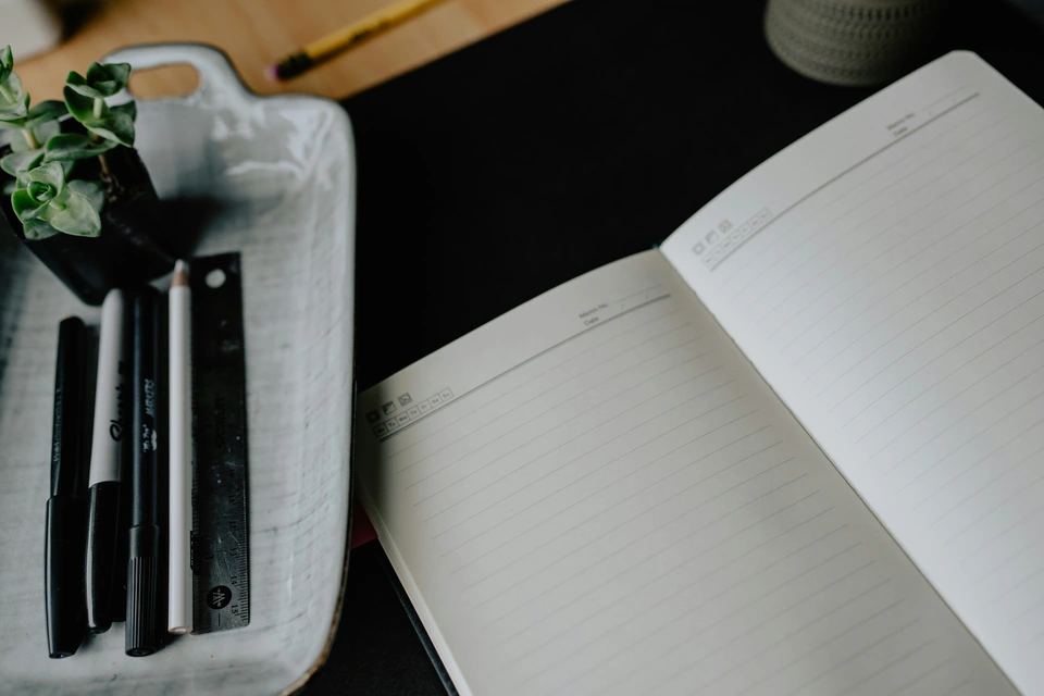 An open notebook and pens on a desk — stock style reference