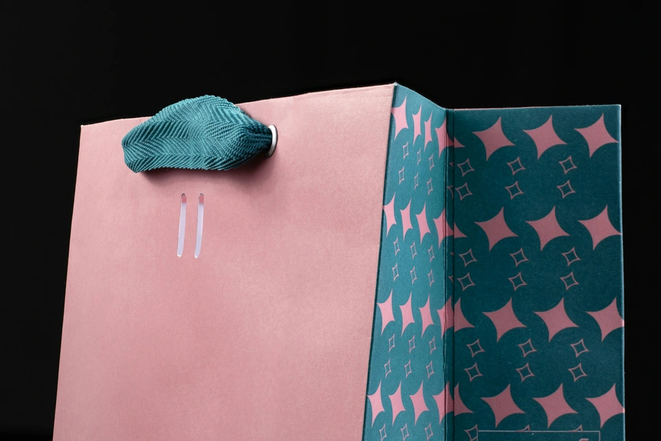 a pink and blue paper bag with a bow on it — stock style reference